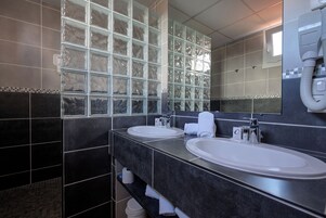 A modern bathroom with two sinks, a large mirror, and a glass block wall.
