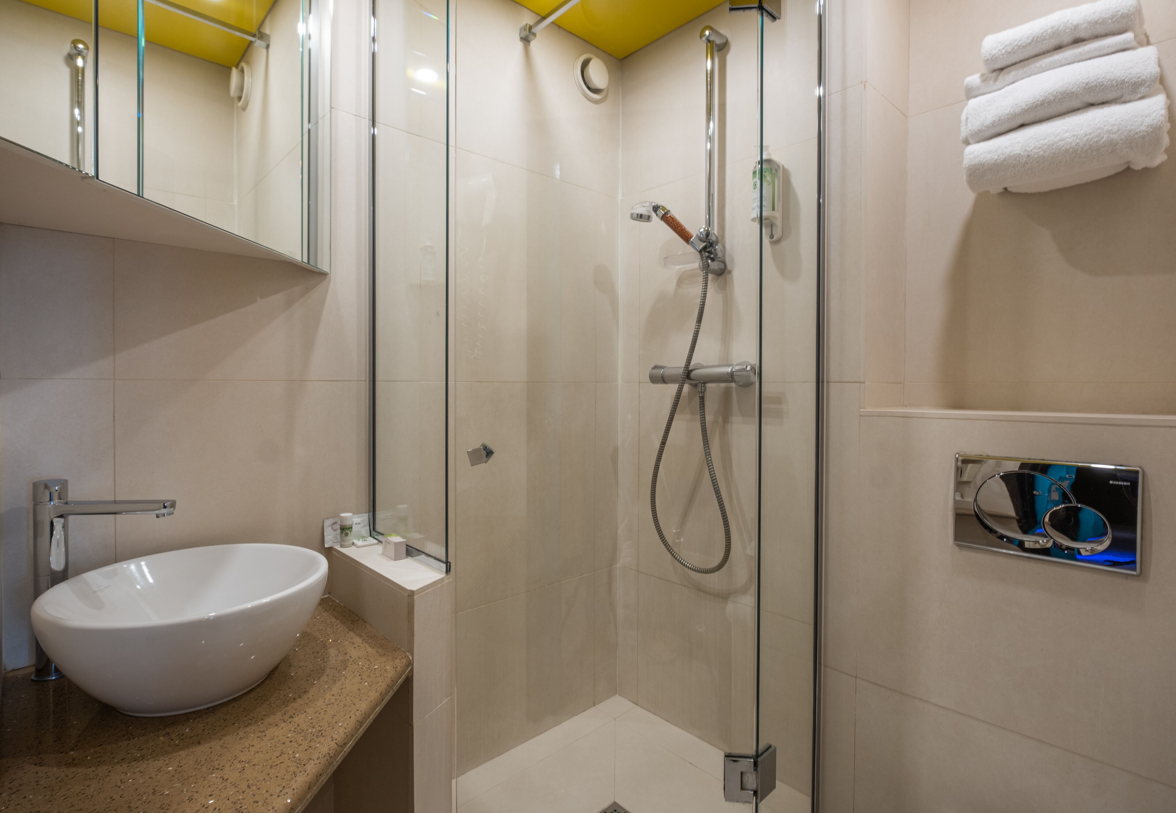 Een badkamer met een wit wastafelmeubel, een glazen douchecabine en een handdoekrek.