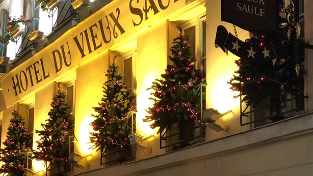 Het uiterlijk van Hotel du Vieux Saulte met verlichte kerstbomen en een bord.
