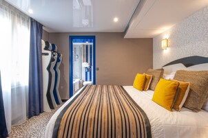 Una habitación de hotel con una cama grande, un baño visible a través de una puerta y una alfombra estampada.
