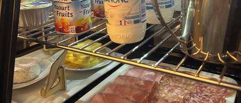 Mostrador de delicatessen con diversos alimentos, incluyendo embutidos y yogures envasados.
