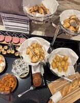 Una mesa de bufé con diversos alimentos, incluyendo pasteles, salsas y aderezos.