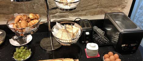 Un bufé de desayuno con pan, bollería y frutas.