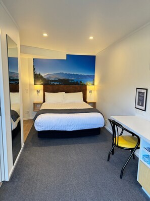 A hotel room with a bed, a desk, a chair, and a large wall mural. - Blue Peaks Lodge (Queenstown)