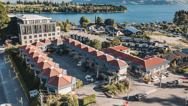 A hotel with a modern building and a parking lot with several cars. - Blue Peaks Lodge (Queenstown)