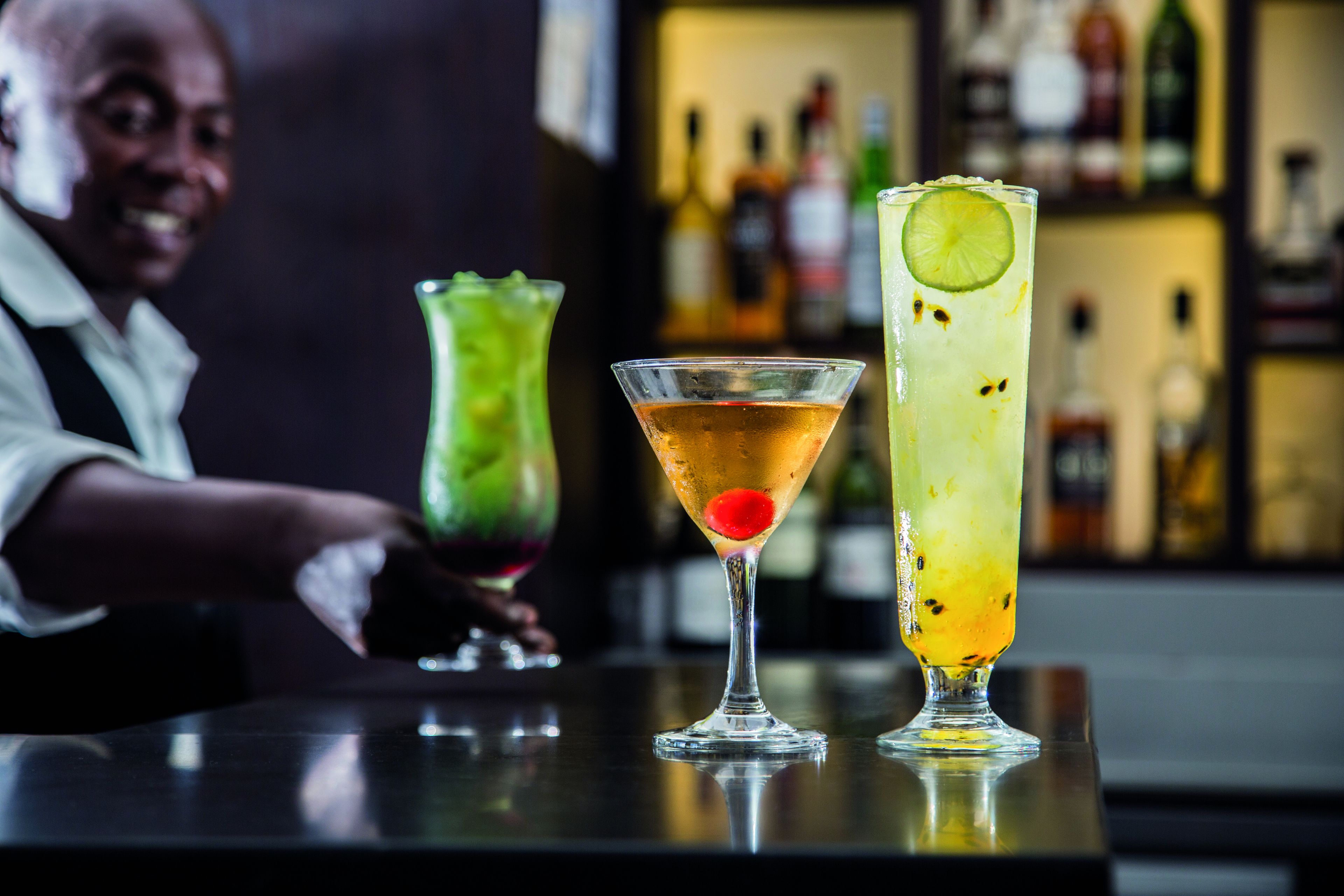 Een bar met drie cocktails op het aanrecht.