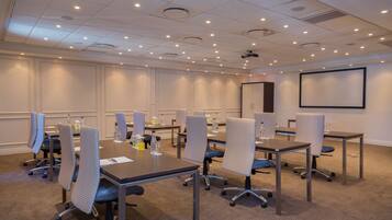A conference room with a large table, multiple chairs, and a projector screen.
