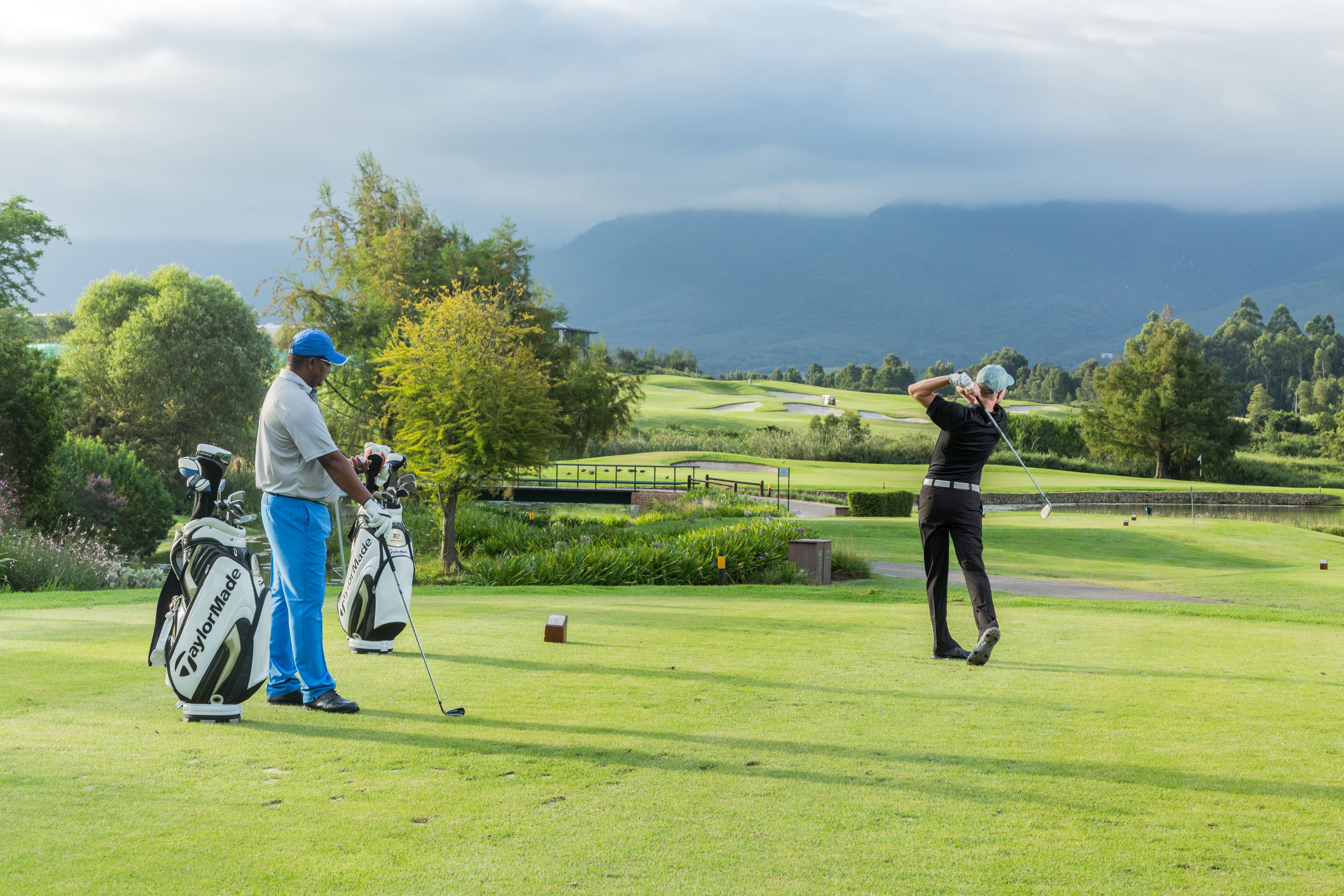 A golf course with players and golf bags.