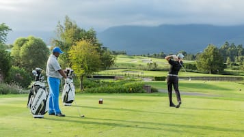 A golf course with players and golf bags.
