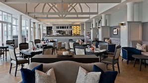 A spacious hotel lobby with high ceilings, large windows, and a central bar area.