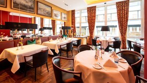 A restaurant with multiple tables set for dining, featuring a classic interior with wooden floors and red accents. - Hotel Baseler Hof (Hamburg)