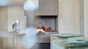 A fireplace with a fire, a mirror, and a vase on the mantel. - Hotel Central (Hamburg)