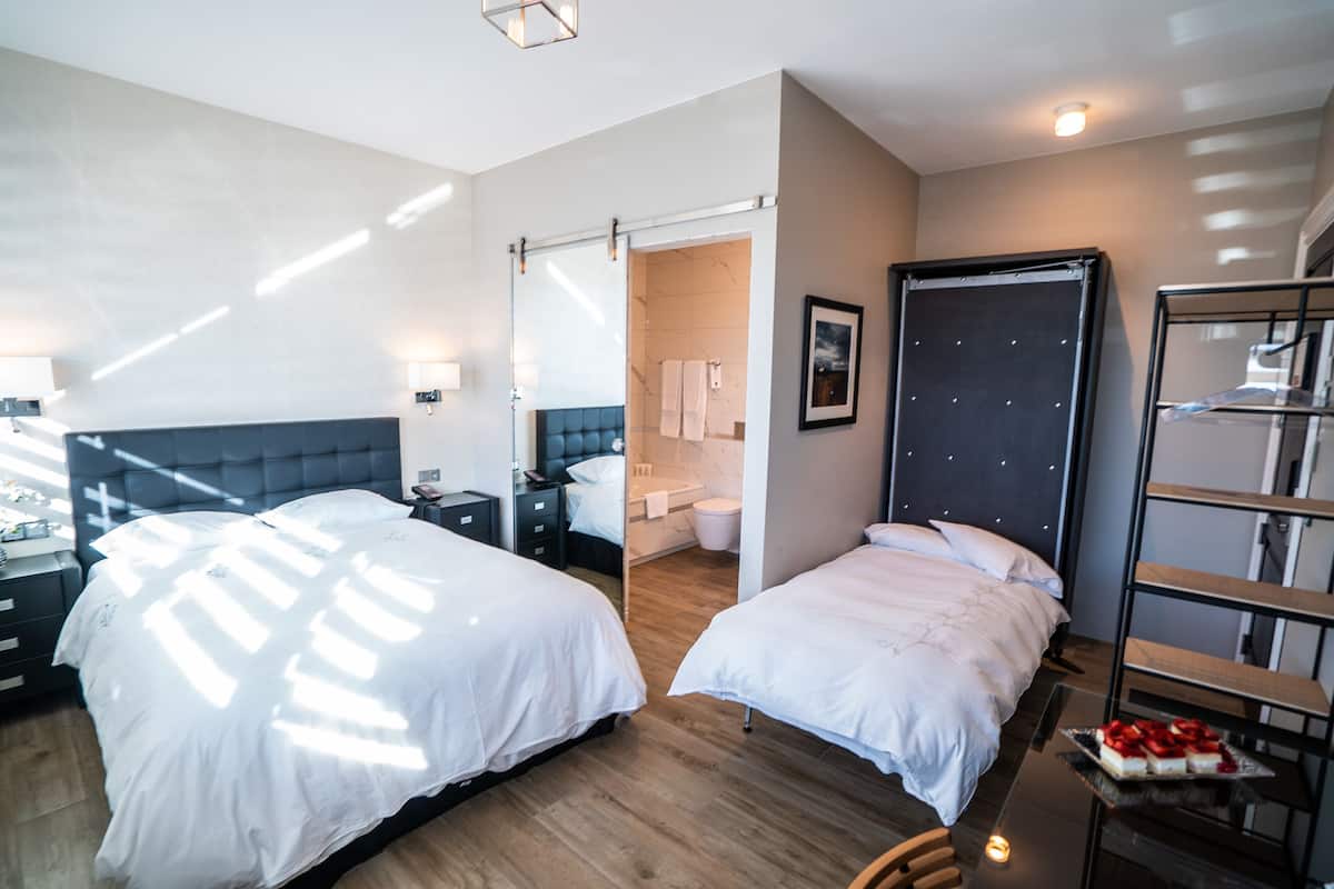 Ein modernes Hotelzimmer mit zwei Betten, einem Badezimmer und einem kleinen Tisch mit einer Obstplatte.