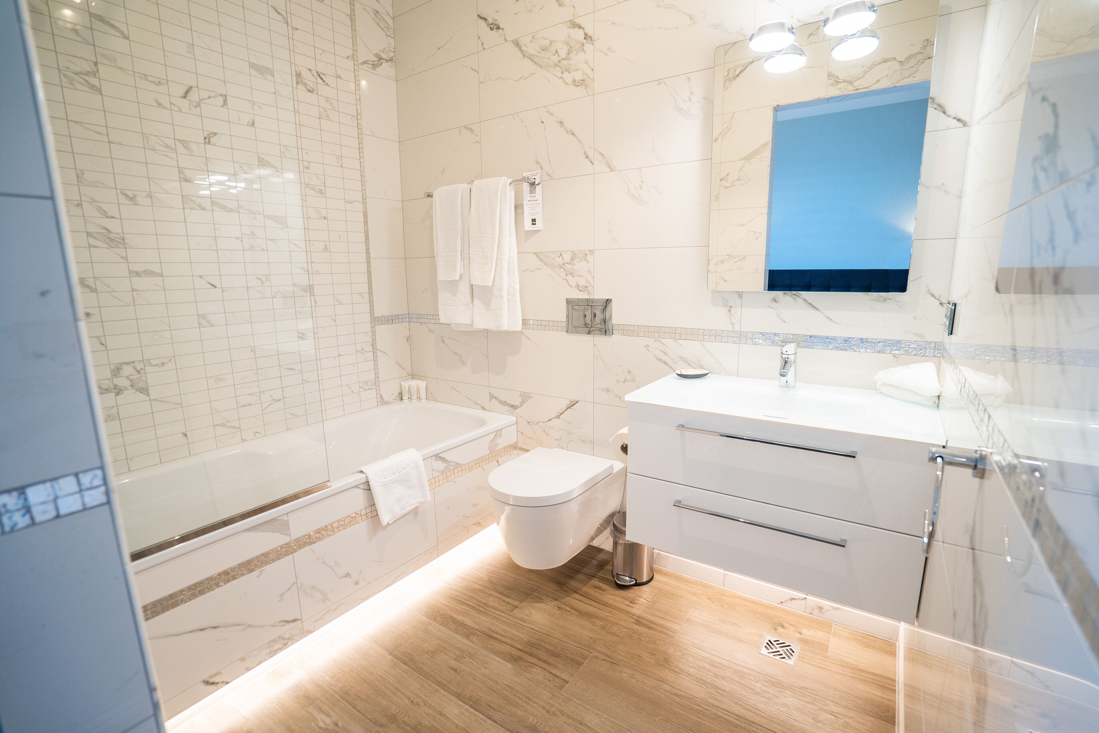 A modern bathroom with a bathtub, toilet, and vanity with a mirror.
