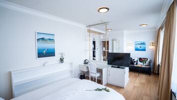 Habitación de hotel con cama, escritorio, televisión y vista al mar.
