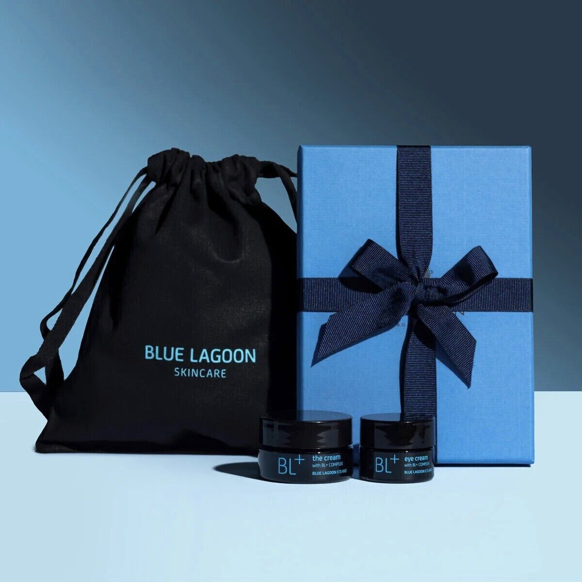 A gift set from Blue Lagoon Skincare, including a black drawstring bag and a blue box with a ribbon, along with two jars of eye cream and cream.