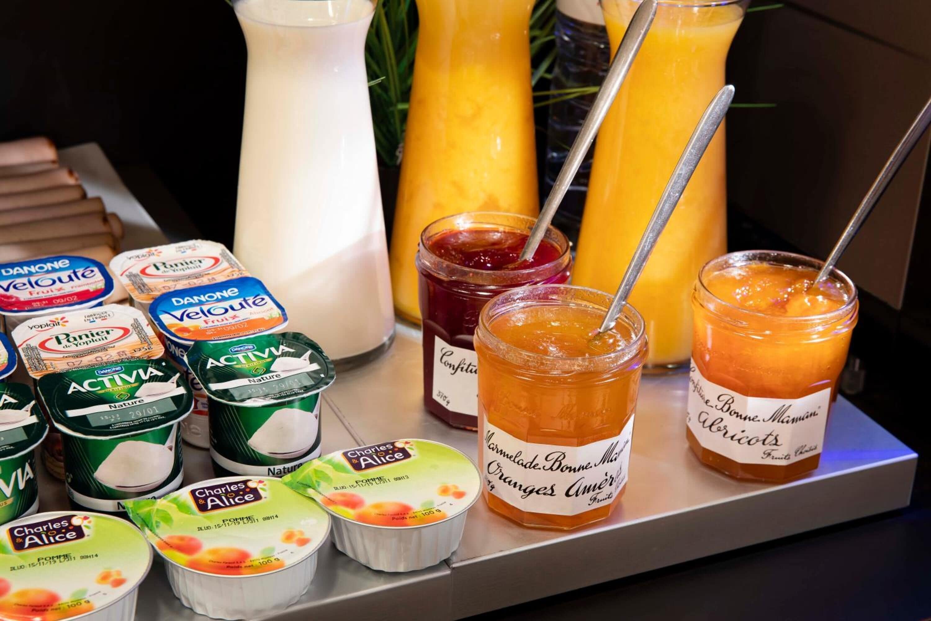 Variedad de productos lácteos como yogur y leche, junto con tarros de mermelada y miel.