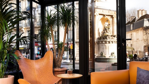 Un espace de détente intérieur avec vue sur un bâtiment historique et une statue.