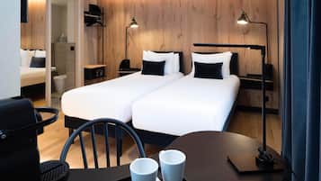 A hotel room with two beds, a desk, a chair, and two bedside lamps.