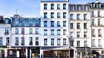A row of white buildings with balconies, including a hotel named "Hôtel du Jardin des Plantes".