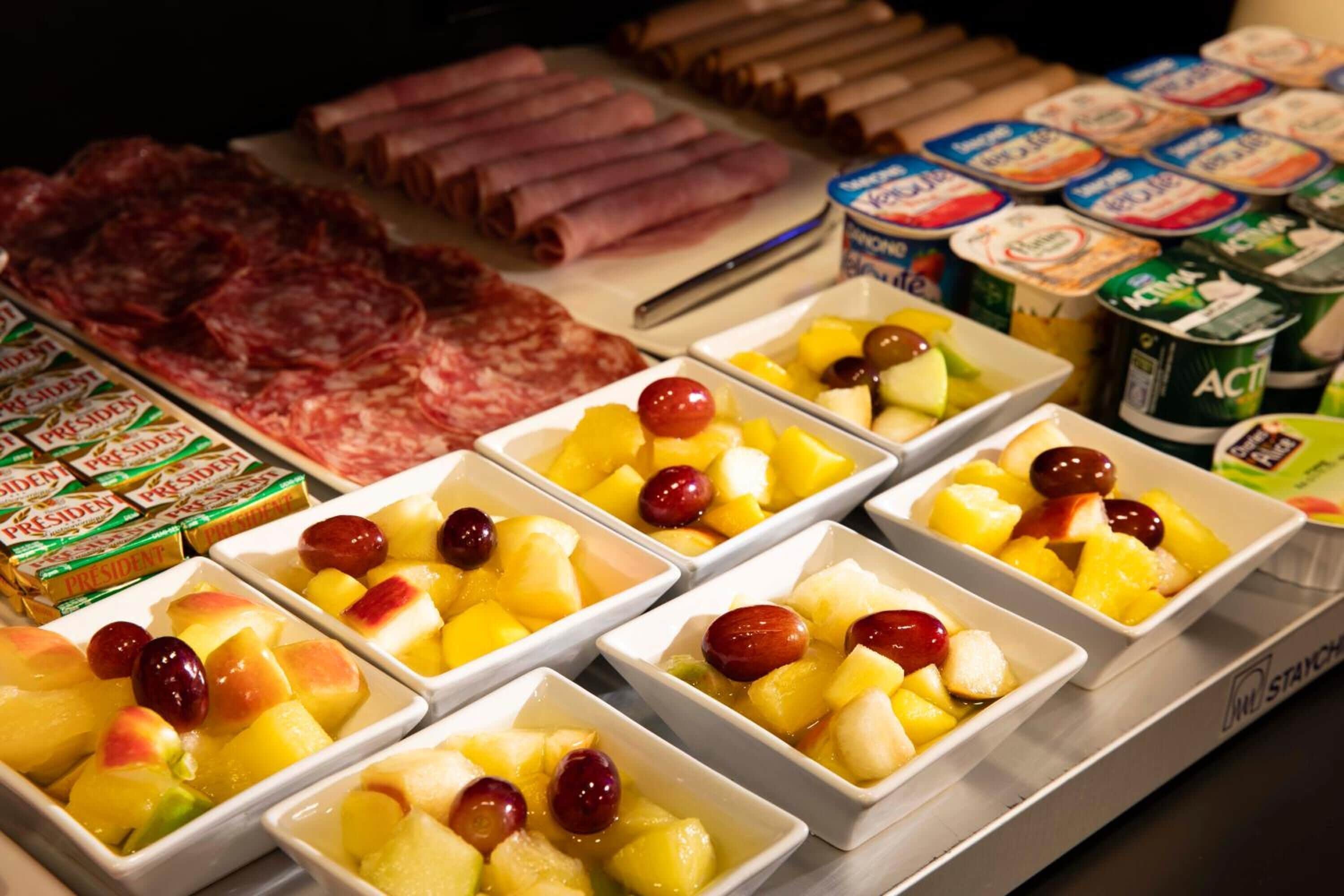 Un assortimento di cibi tra cui carni, formaggi e ciotole di frutta.