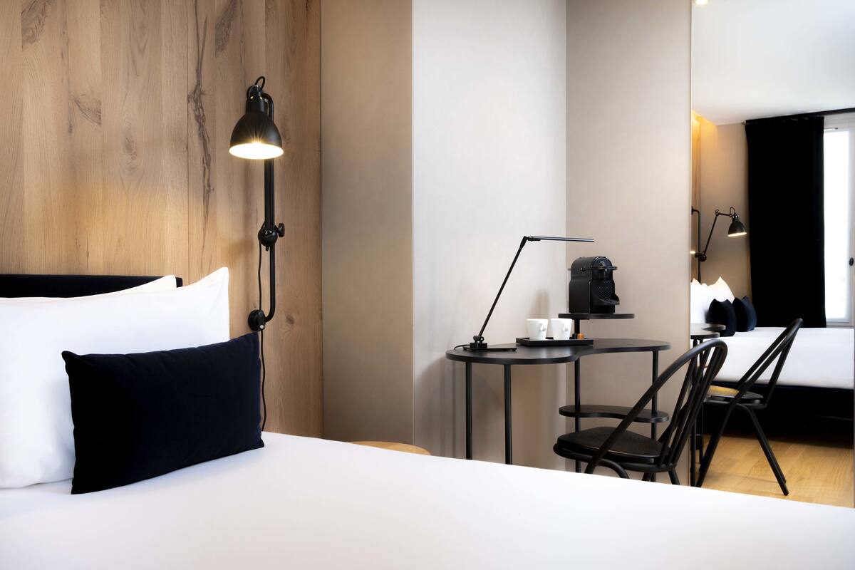 Een hotelkamer met een bed, een bureau, een stoel, een lamp en een spiegel.