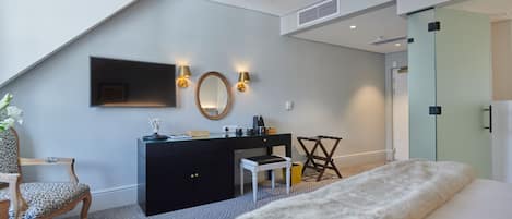 A modern bedroom with a bed, a desk, a chair, a mirror, and wall-mounted lights.