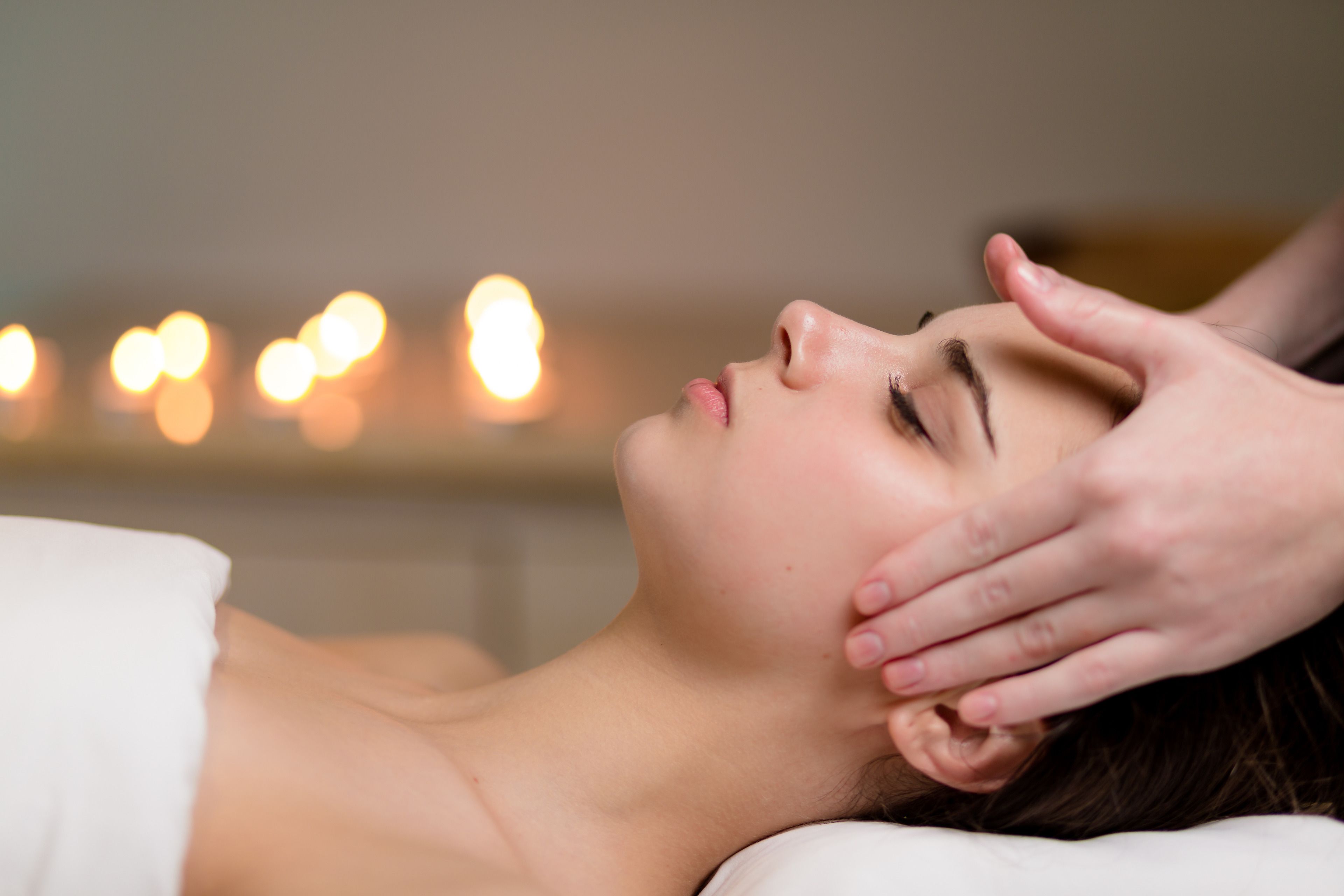 A person lying down with a hand on their head, possibly receiving a massage.