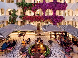 A courtyard with outdoor seating, a central fountain, and a building with arches in the background. - The Winchester Hotel by NEWMARK (Cape Town)
