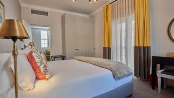 A hotel room with a large bed, a desk, a chair, and a lamp.