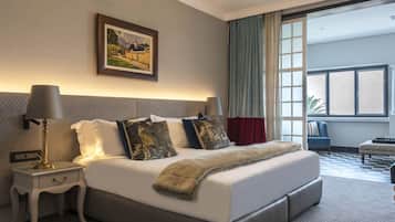 Una habitación de hotel moderna con una cama grande, una mesita de noche, una lámpara, un cuadro en la pared y vistas al exterior a través de una ventana.