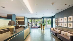 Un hall d’hôtel moderne, doté d’un comptoir d’accueil, d’un espace salon et d’œuvres d’art encadrées qui ornent les murs.