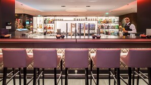 A bar area with seating, a bar counter, and a variety of bottles and glasses.