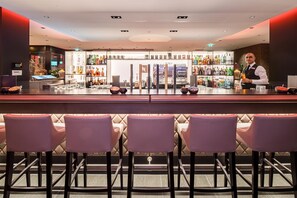 Un espace bar avec des sièges, un comptoir et une variété de bouteilles et de verres.