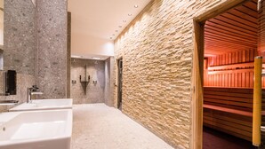 A modern bathroom with a stone wall, a wooden sauna, and a large sink.