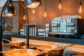 Un moderno café con máquina Nespresso, varios dispensadores de café y una variedad de cápsulas.