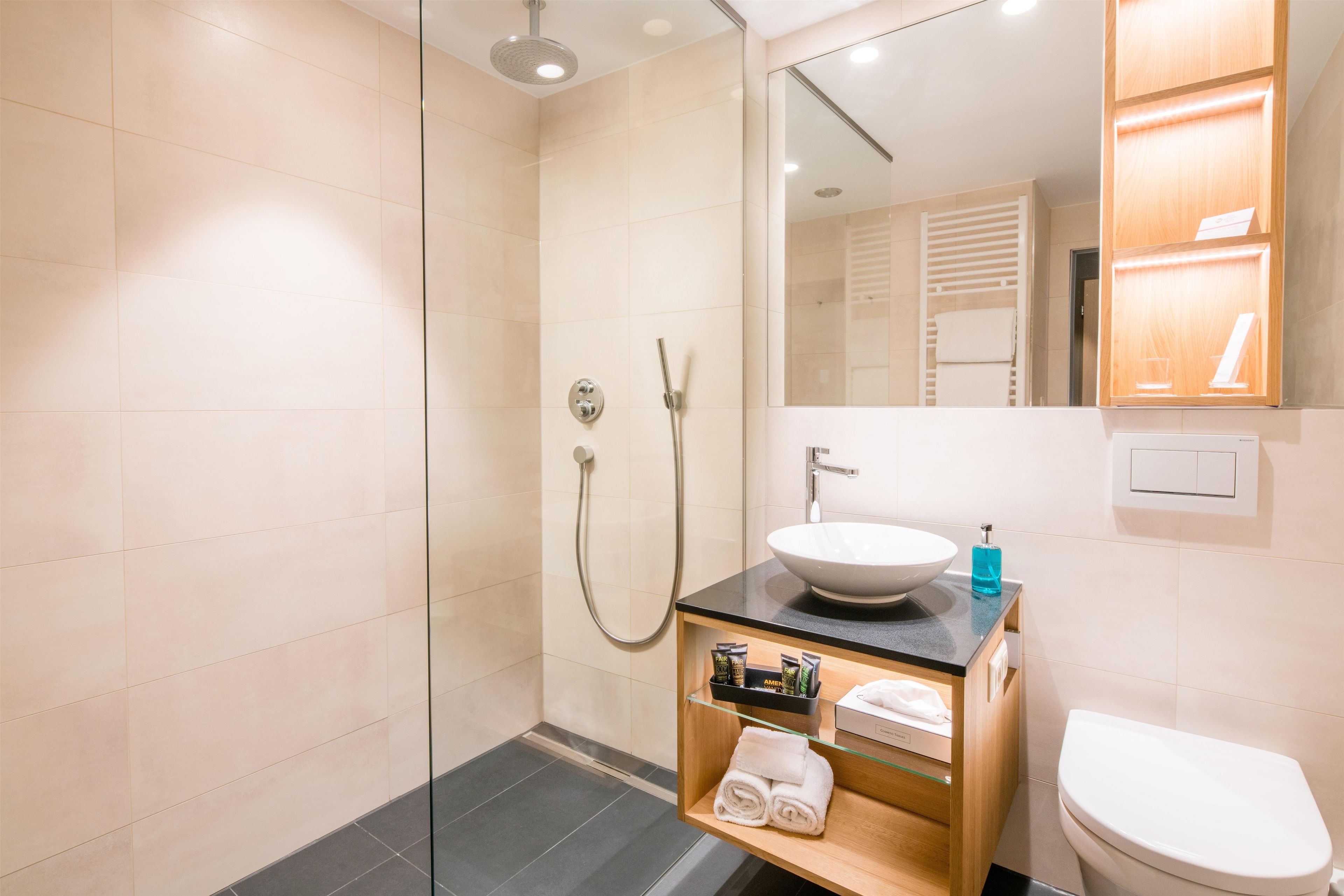 A modern bathroom with a glass-enclosed shower, a sink with a black countertop, and a toilet.