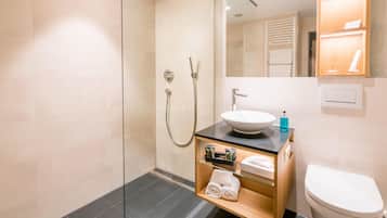 A modern bathroom with a glass-enclosed shower, a sink with a black countertop, and a toilet.