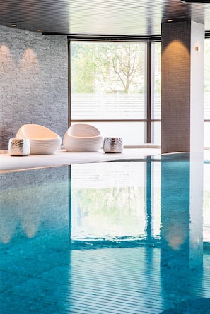 Une piscine intérieure offrant une vue dégagée sur l’extérieur grâce à de grandes fenêtres.