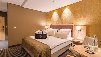 A hotel room with a bed, bedside tables, a desk with a chair, and a wall-mounted lamp.