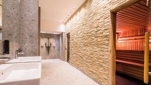 Une salle de bain moderne avec deux lavabos, un mur en pierre et un espace sauna.