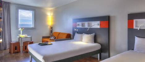 A hotel room with a bed, bedside tables, a desk, a chair, and a window.