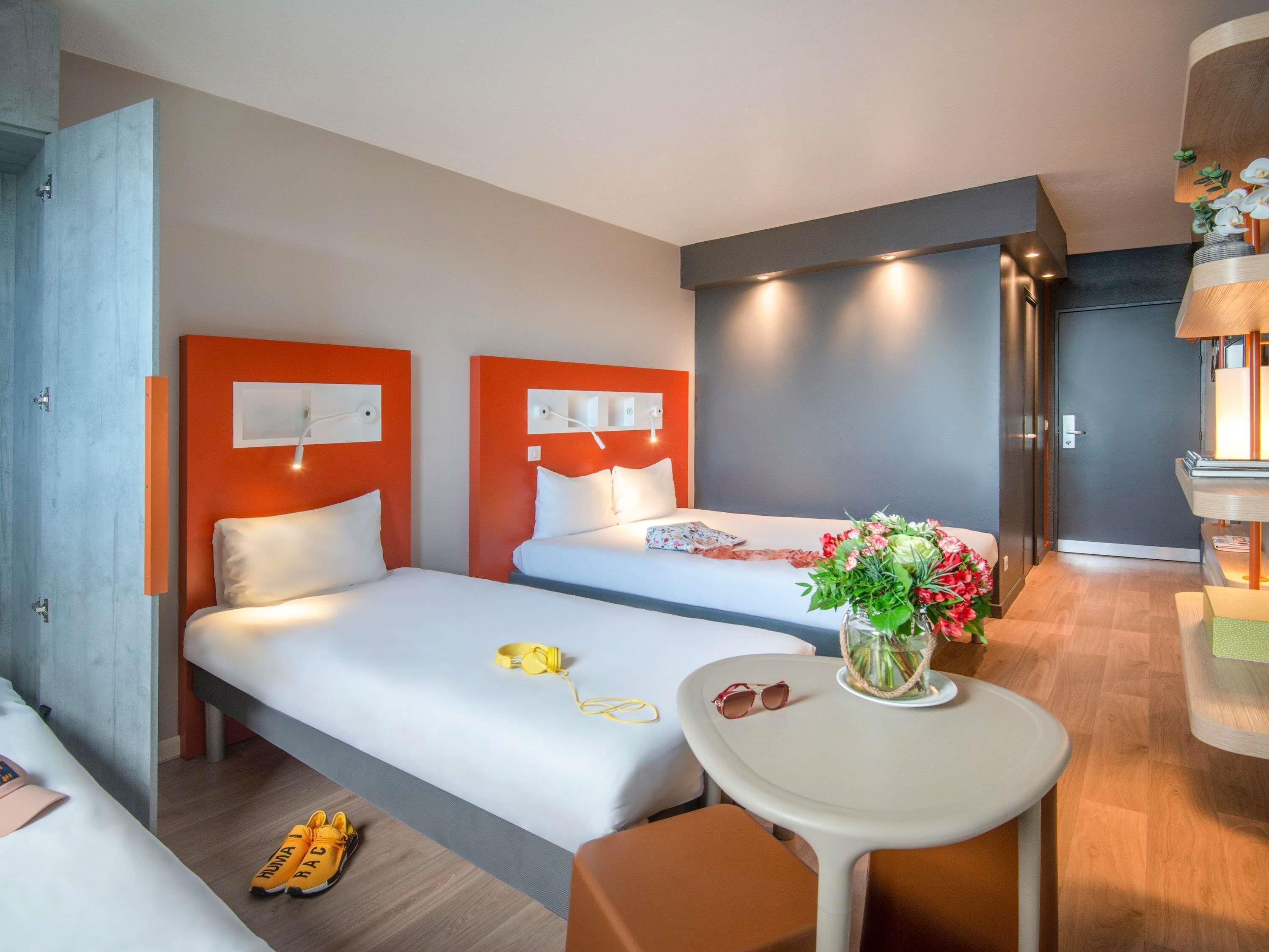 Een hotelkamer met twee bedden, een tafeltje en een bureau met een lamp.