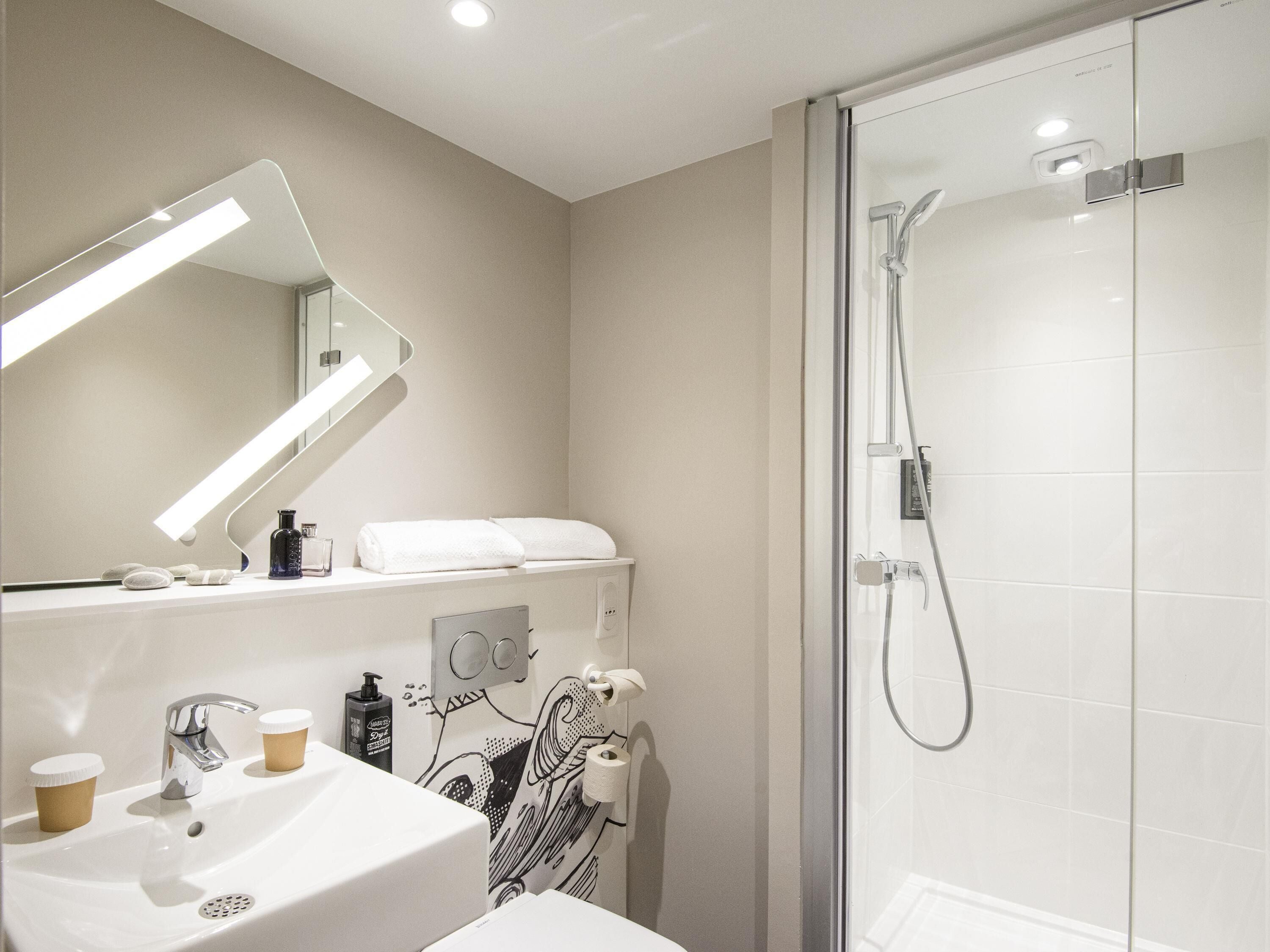 A modern bathroom with a glass shower enclosure, a sink with a mirror, and a towel rack.