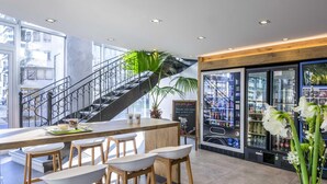 Ein modernes Interieur mit Barbereich, Sitzgelegenheiten, einer Treppe und einem Automaten.