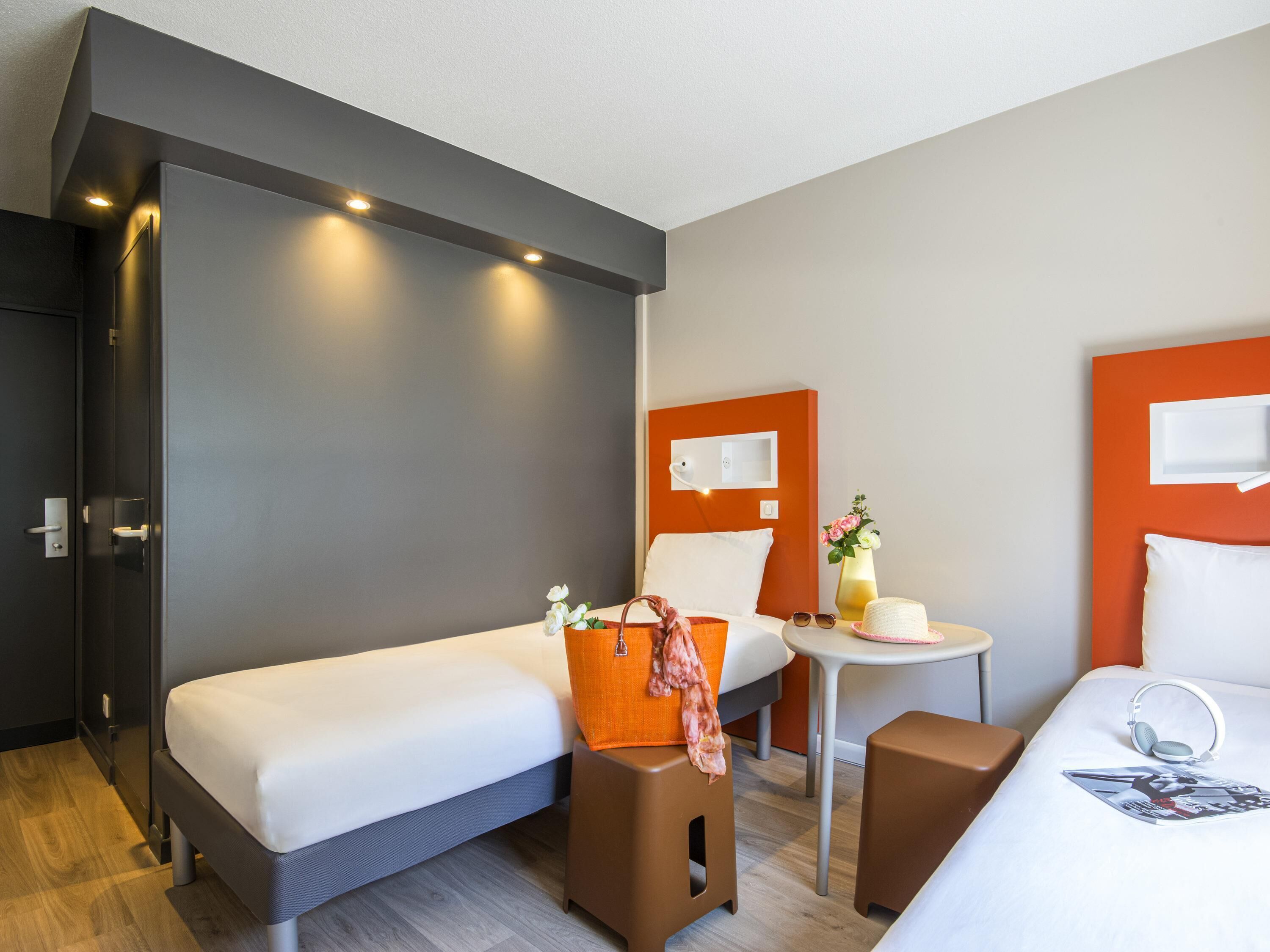 Una habitación de hotel con dos camas, una mesita pequeña y una silla.