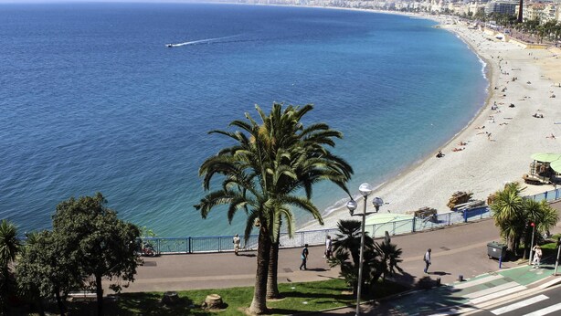 Eine Küstenstadt mit Strand, Palmen und blauem Himmel.
