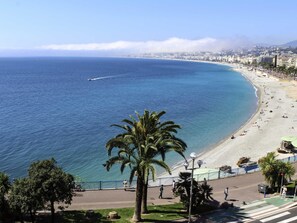 A coastal cityscape with a beach, palm trees, and a clear sky. - ibis budget Nice Californie Lenval (Nice)