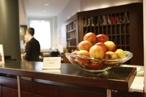 A glass bowl of apples on a wooden counter with a sign reading "Fresh from the orchard."