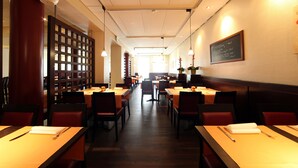 A restaurant with wooden tables and chairs, a high ceiling, and a menu on the wall. - Dietrich-Bonhoeffer-Hotel (Berlin)